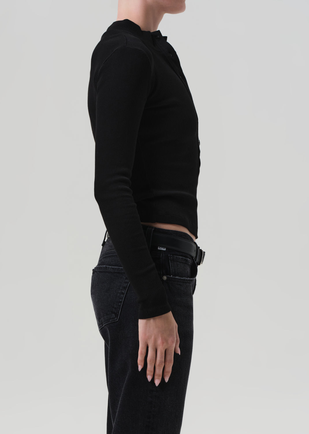 Person wearing a black long-sleeve top and black pants on a light gray background