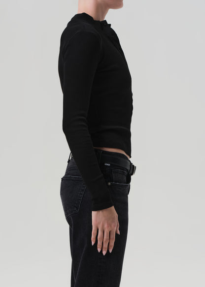 Person wearing a black long-sleeve top and black pants on a light gray background