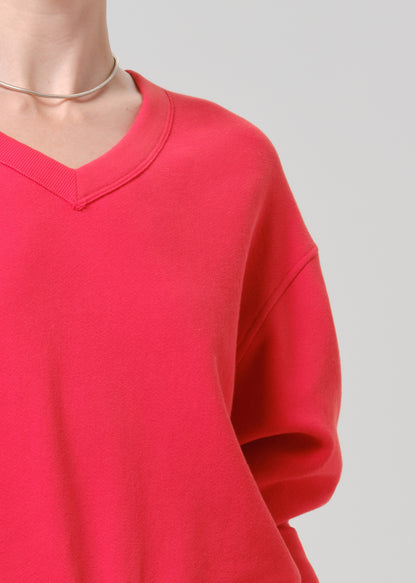 Person wearing a bright pink V neck sweater on a grey background