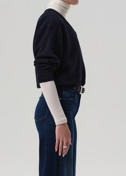 Person wearing a navy sweater and blue jeans on a plain background