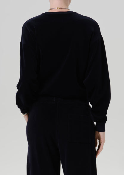 A person shown from the back wearing a dark navy long-sleeve top and matching dark navy pants against a grey background.