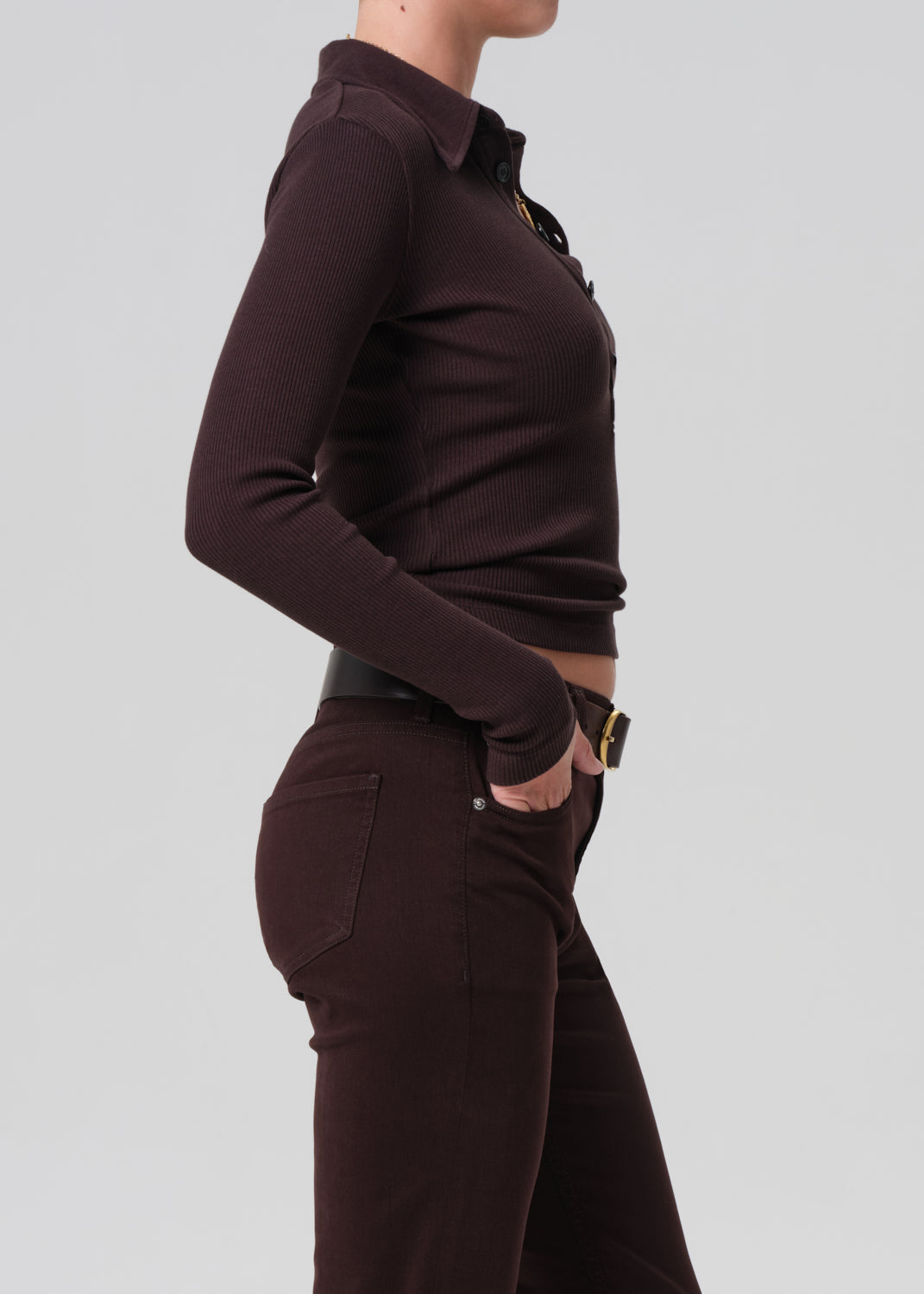 Person wearing a brown long-sleeve top and brown pants on a light gray background