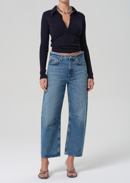 Person wearing a navy long-sleeve top and blue jeans on a grey background