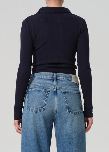 Person wearing a navy long-sleeve shirt and blue jeans on a light gray background