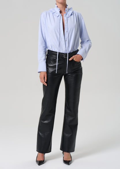 Person wearing a light blue shirt and black leather pants on a white background