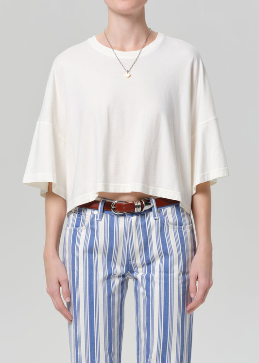 Person wearing a white top and blue striped pants on a gray background