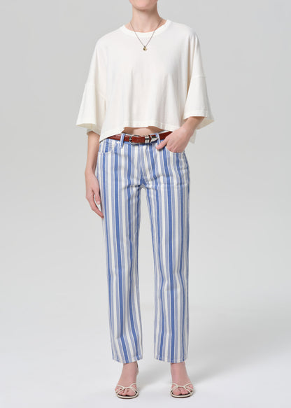 Person wearing a white top and blue striped pants on a plain background