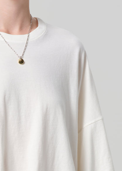 White sweater worn by a person with a necklace on a plain background