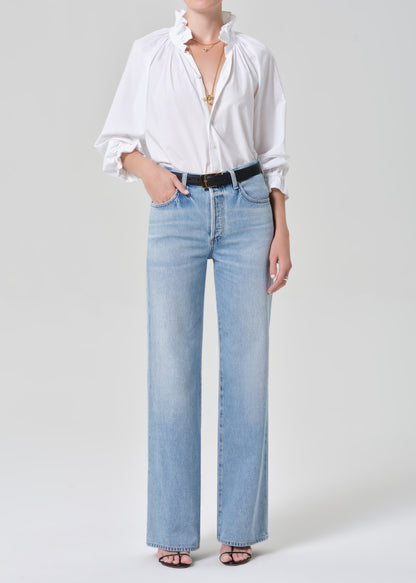 Person wearing a white shirt and light blue jeans on a plain background