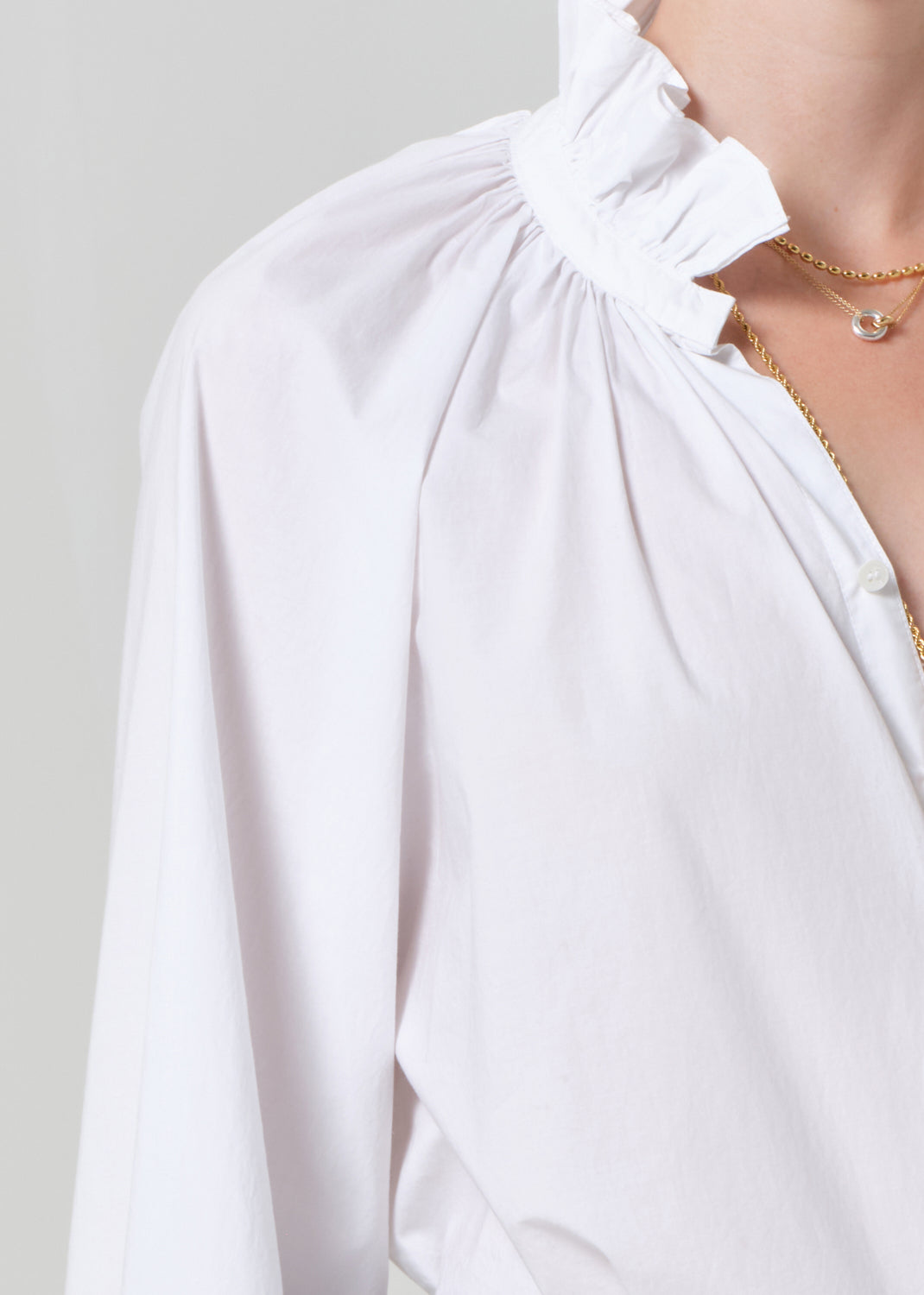 White blouse with a ruffled neckline on a plain background