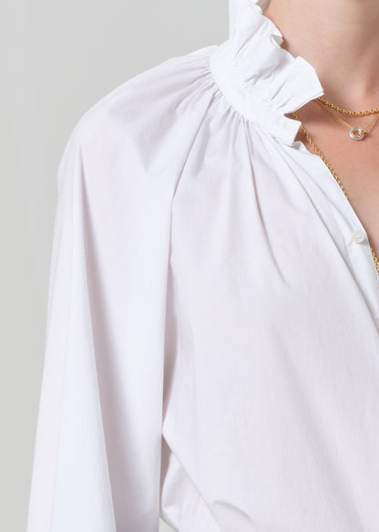 White blouse with a ruffled neckline on a plain background