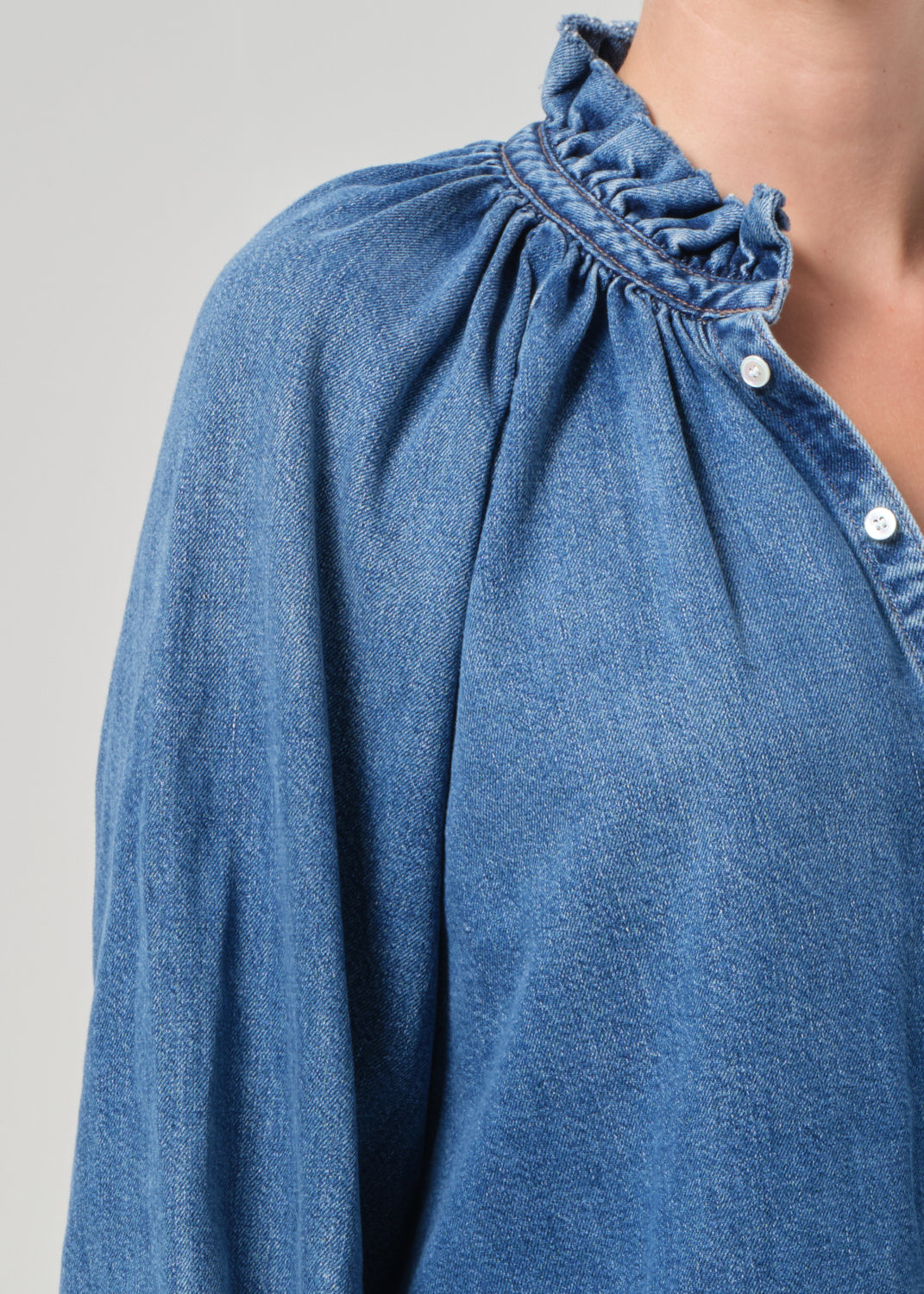 Close-up of a blue denim shirt with a gray background