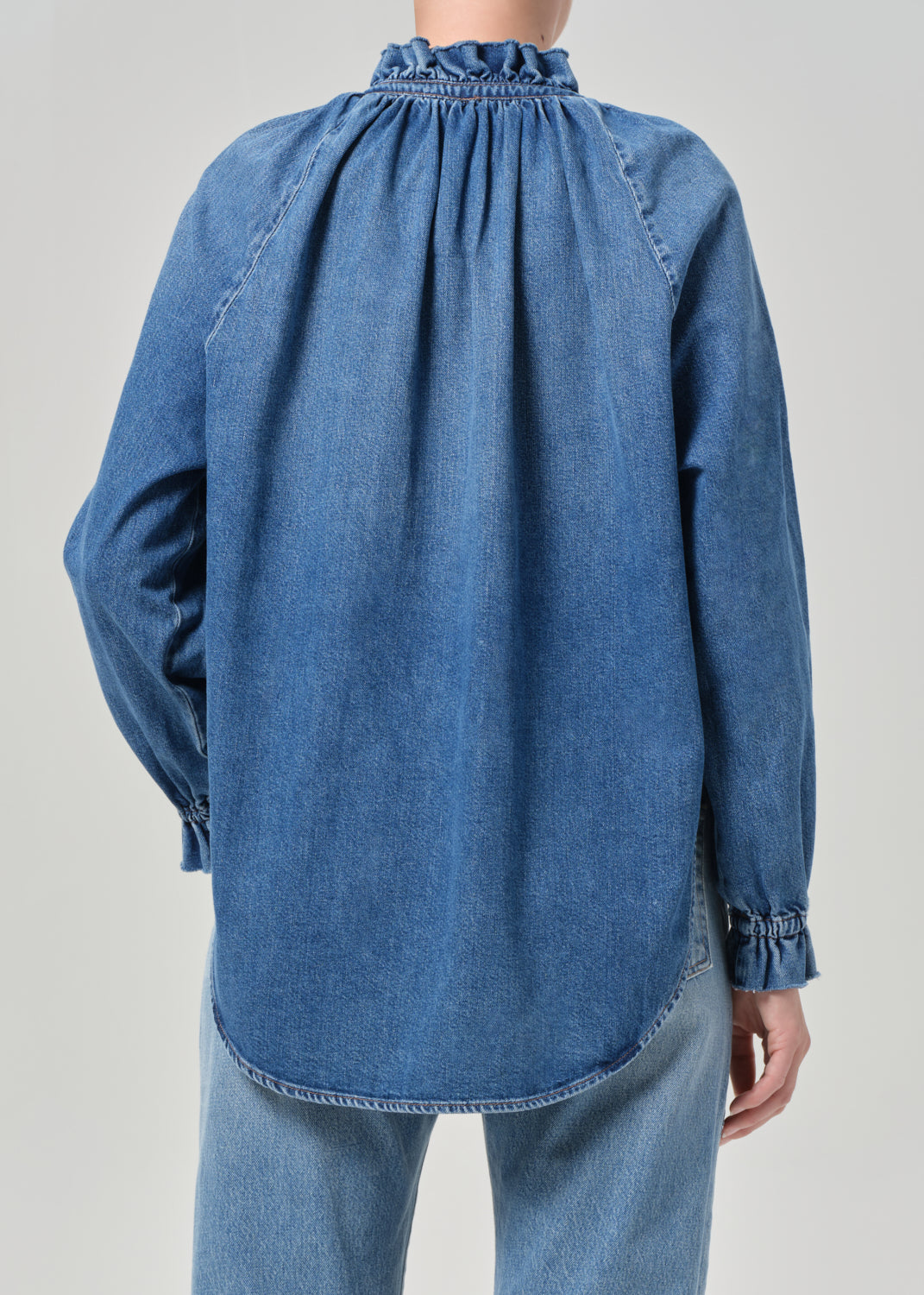 Blue denim shirt worn by a person on a gray background