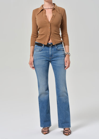 Person wearing a brown button-up shirt and blue jeans on a white background