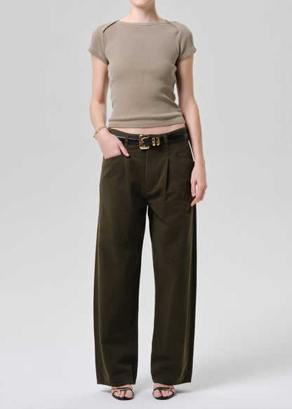 Person wearing a beige top and brown wide-leg pants on a grey background.