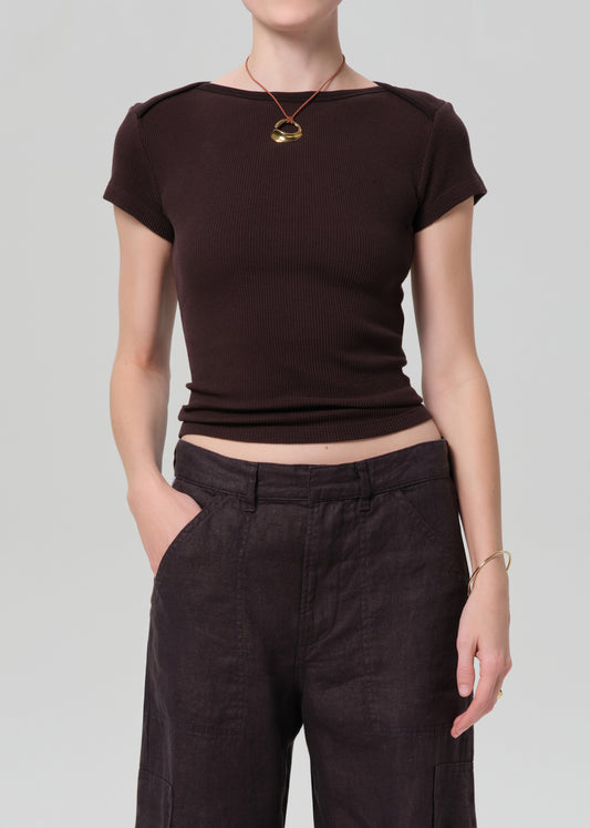 Person wearing a brown crop top and dark pants on a plain background