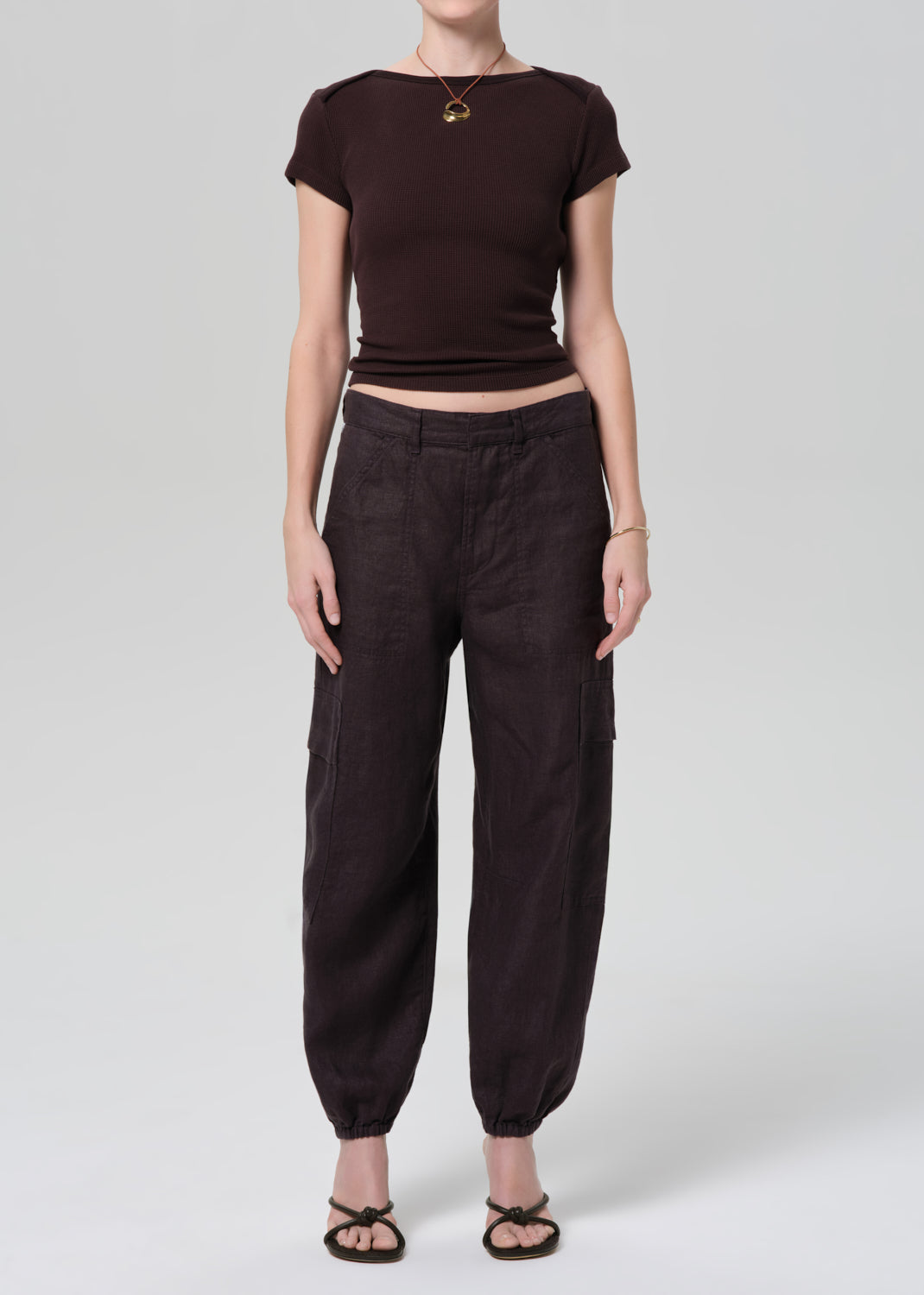 Person wearing a brown crop top and baggy pants on a grey background