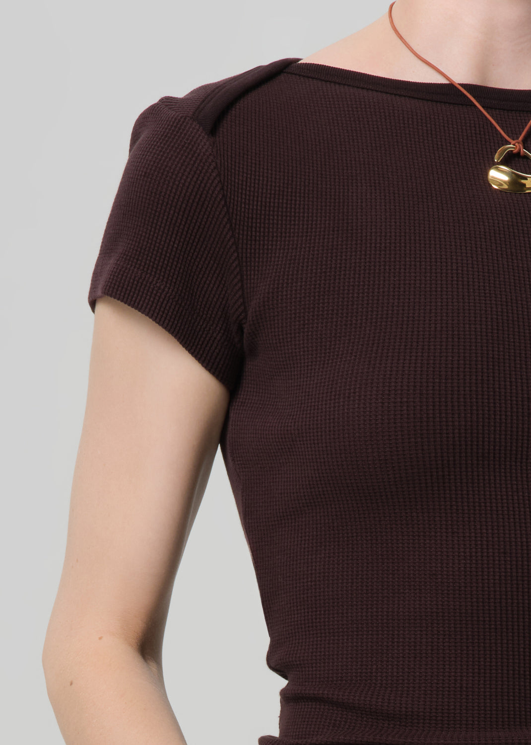 Brown ribbed top worn by a person on a gray background