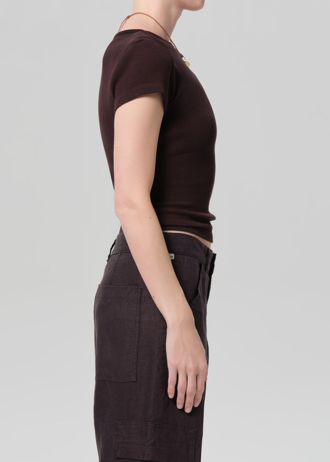 Person wearing a brown t-shirt and pants on a light gray background