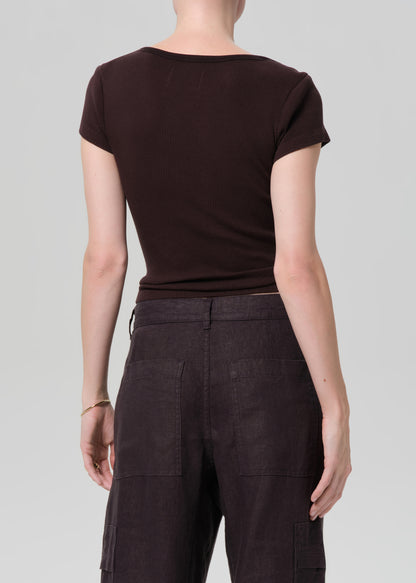 Person wearing a brown t-shirt and dark pants on a light gray background