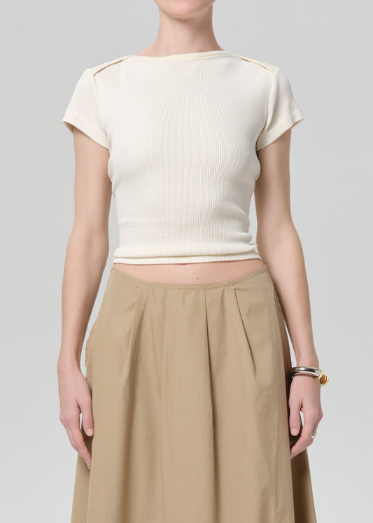 Person wearing a cream top and beige skirt on a plain background