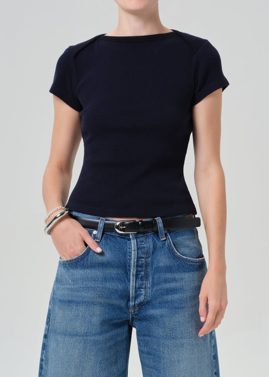 Person wearing a navy top and blue jean shorts on a gray background