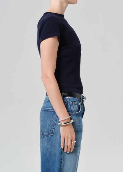 Person wearing a navy top and blue jean shorts on a gray background