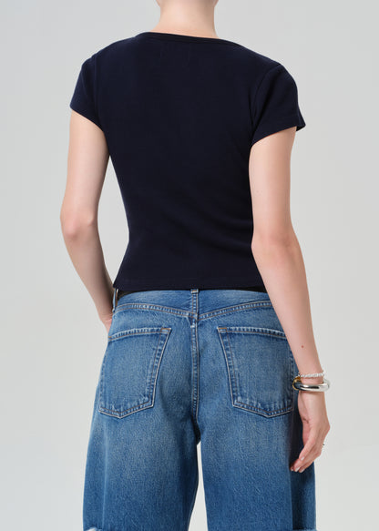 Person wearing a navy top and blue jean shorts on a gray background