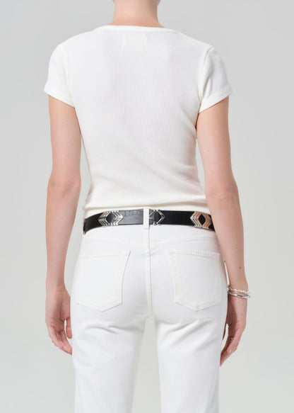 Person wearing a white t-shirt and white pants with a black belt featuring accents on a light gray background