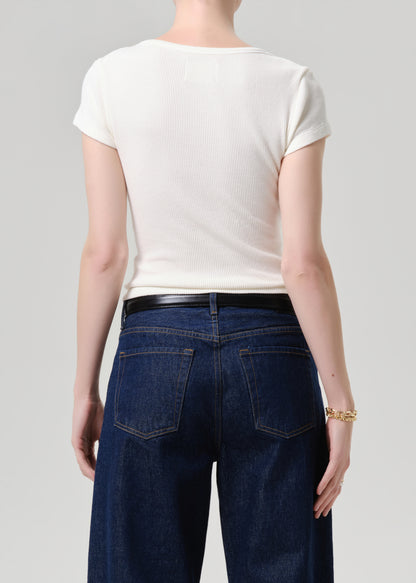 A model shown from the back wearing a fitted off-white short-sleeve t-shirt and dark blue wide-leg jeans with a black belt, against a grey background.