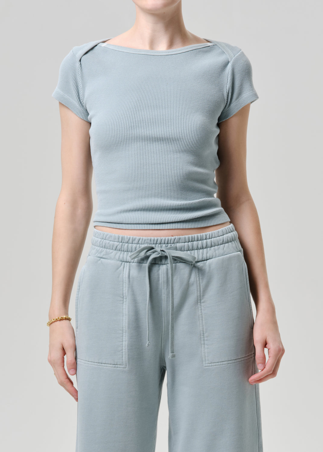 Person wearing a light blue ribbed top and matching pants on a grey background