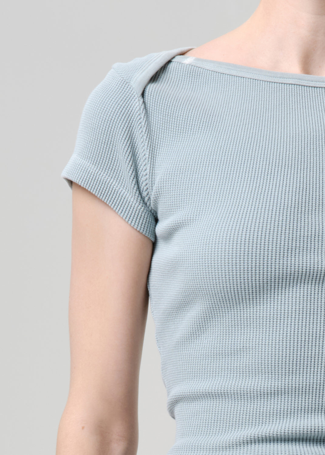 Light blue ribbed top worn by a person on a grey background