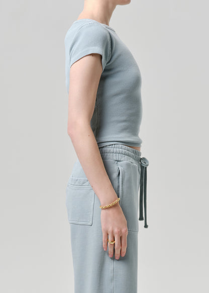 Person wearing a light gray ribbed sweater and pants on a grey background