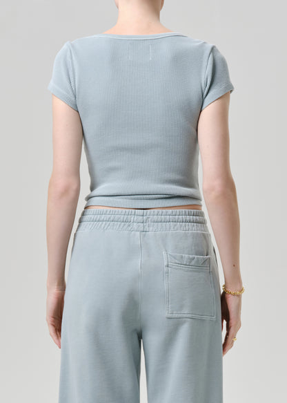 Person wearing a light blue ribbed top and matching pants on a grey background