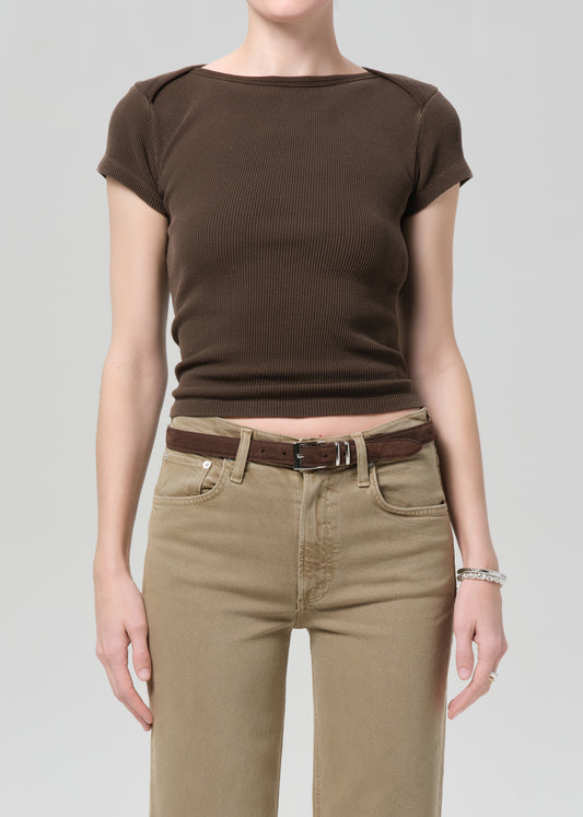Person wearing a brown top and beige pants on a plain background