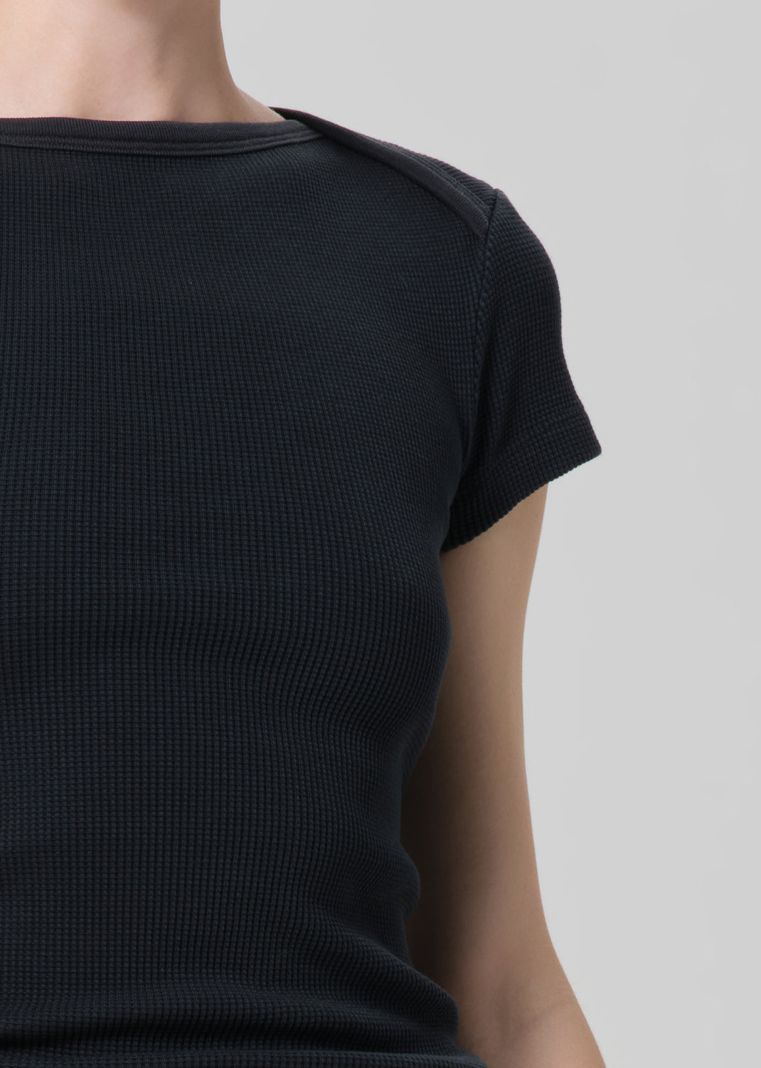 Black ribbed t-shirt worn by a person on a light gray background