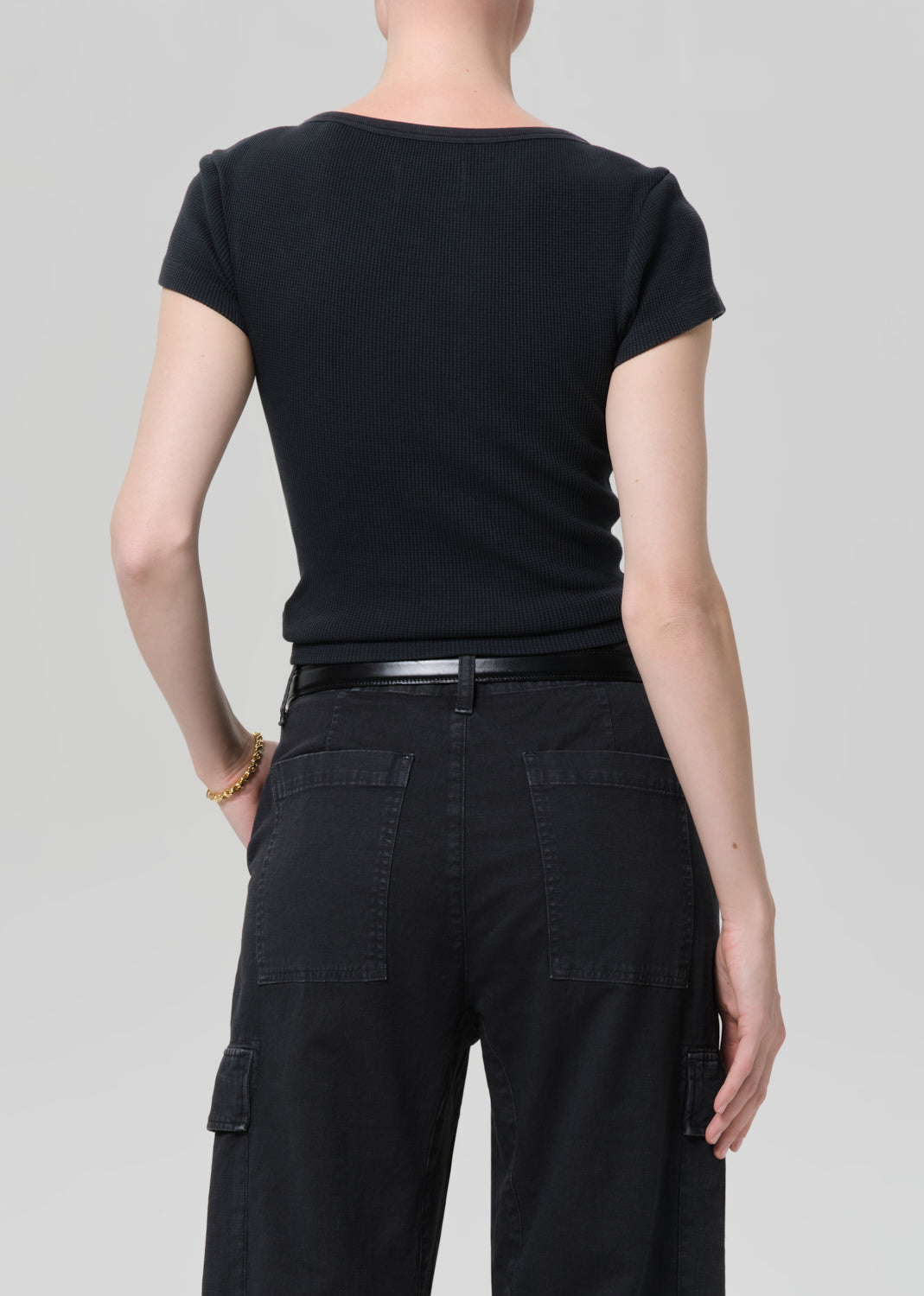 Person wearing a black t-shirt and black cargo pants on a light gray background