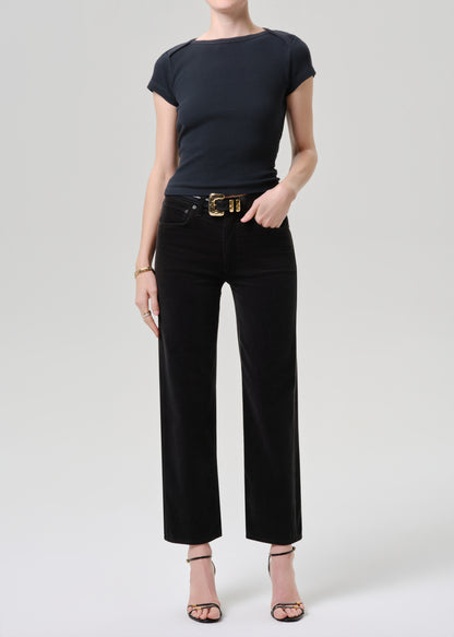 Person wearing a black t-shirt and black pants with a gold belt on a grey background