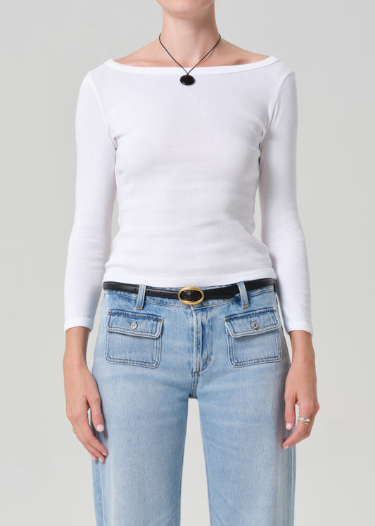 Person wearing a white long-sleeve top and light blue jeans on a gray background