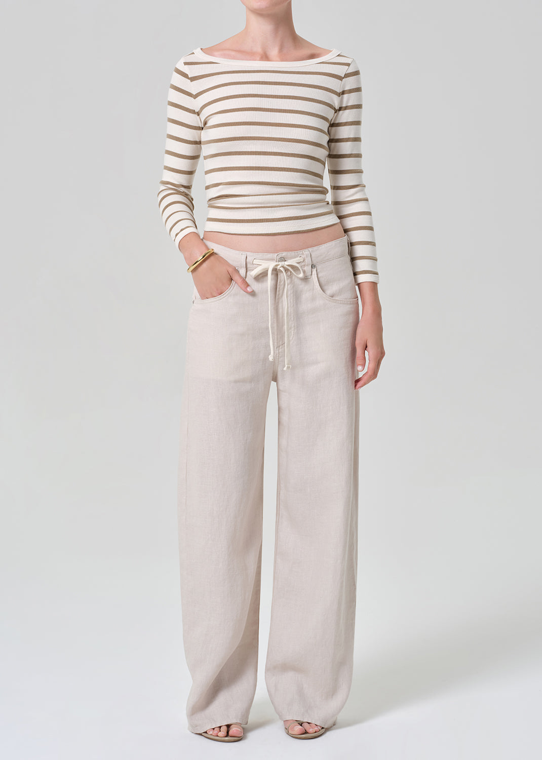 Person wearing a striped long-sleeve top and wide-leg pants on a grey background