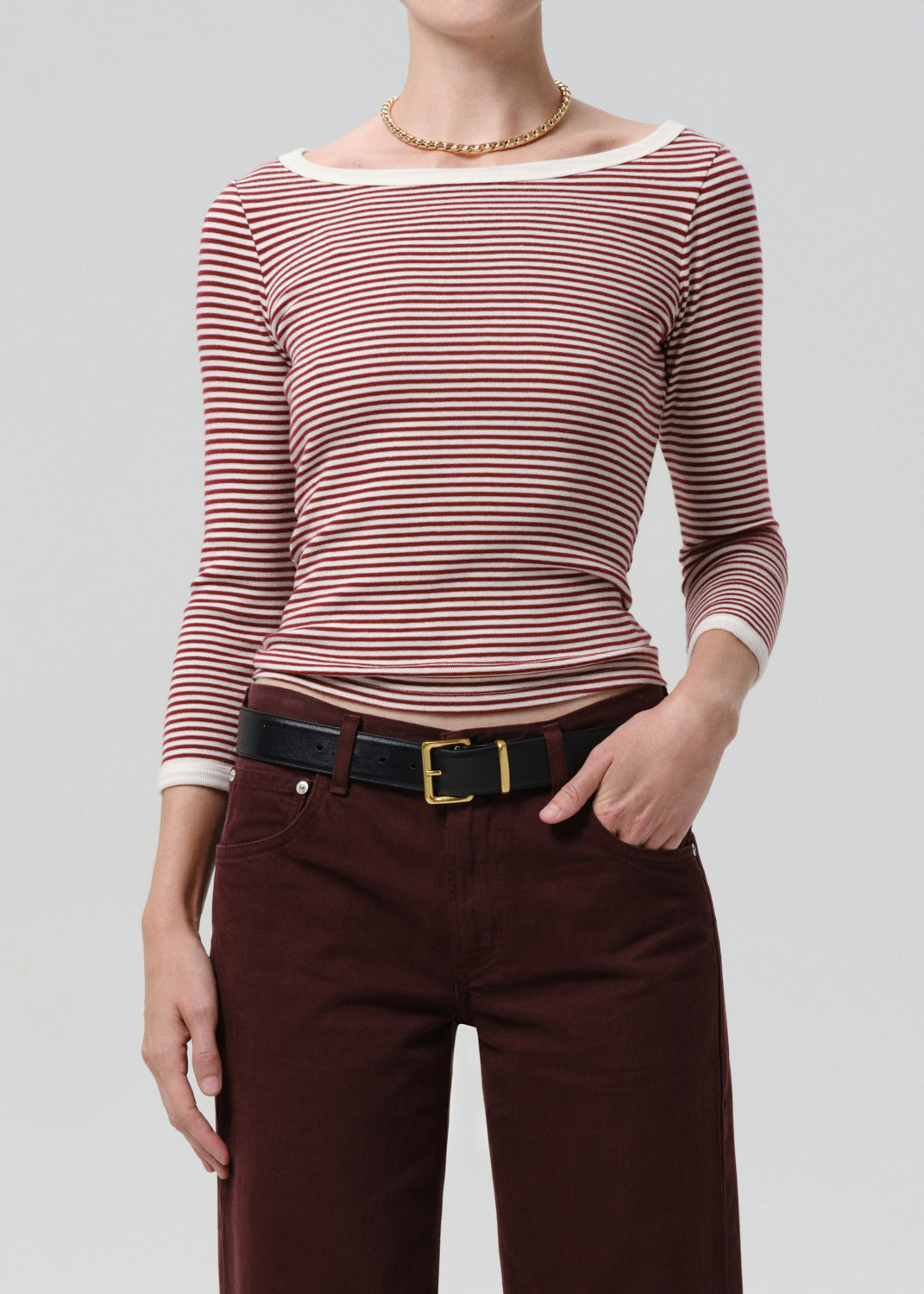 Person wearing a red and white striped shirt with maroon pants on a grey background