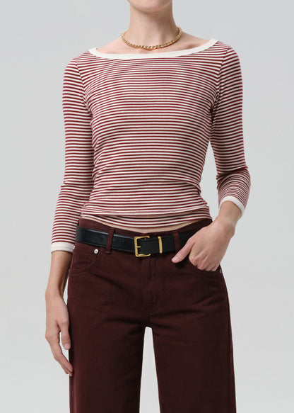 Person wearing a red and white striped shirt with maroon pants on a grey background