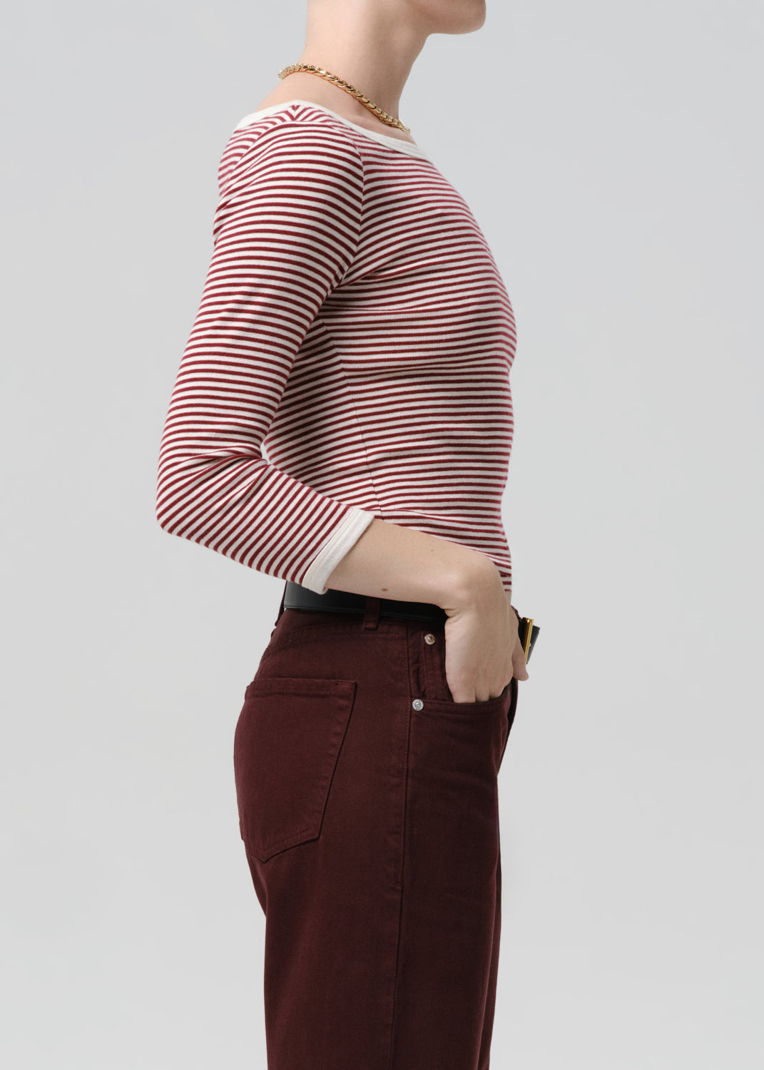 Person wearing a red and white striped long-sleeve shirt and brown pants on a grey background