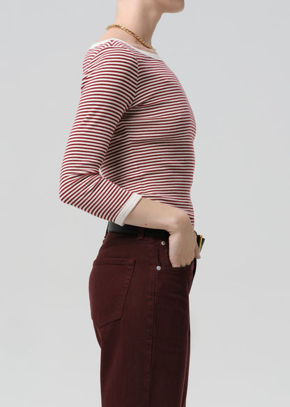 Person wearing a red and white striped long-sleeve shirt and brown pants on a grey background