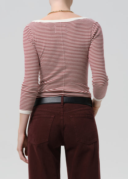 Person wearing a red and white striped shirt with maroon pants on a grey  background