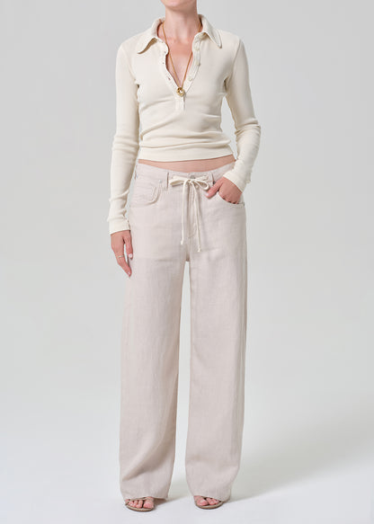 Person wearing a cream-colored long-sleeve shirt and light-colored pants on a plain background