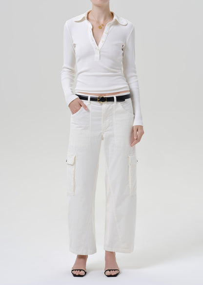 Person wearing white polo top with white pants on a grey background