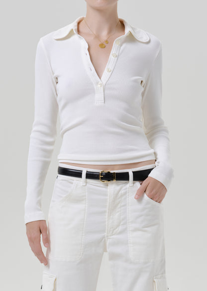 Person wearing white polo top with white pants on a grey background