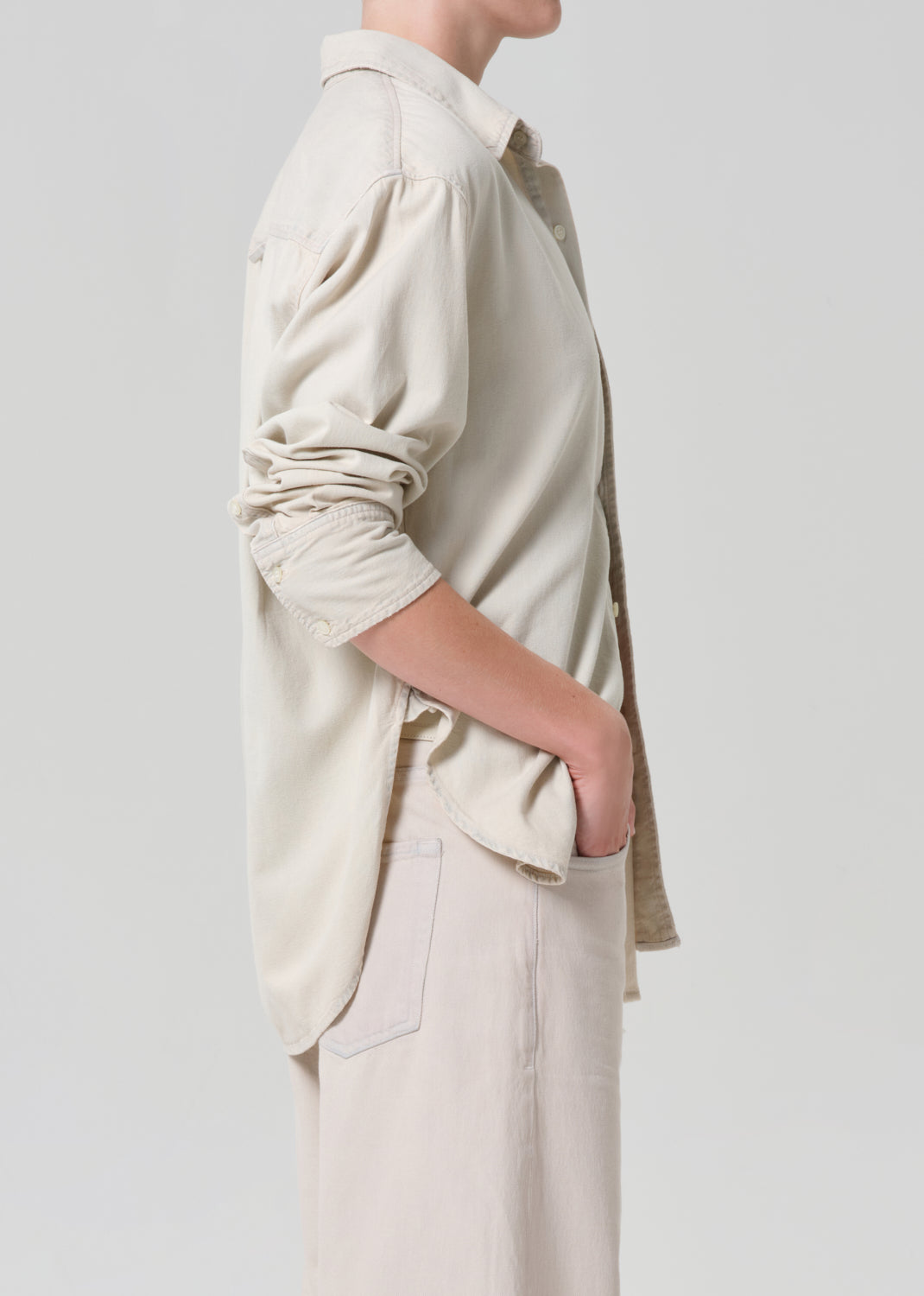 Person wearing a beige shirt and pants on a plain background