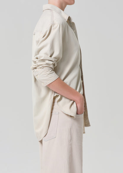 Person wearing a beige shirt and pants on a plain background